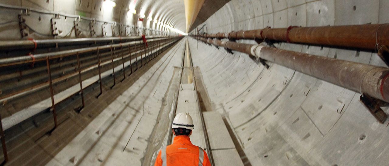worker walking down underground pipe tunnel 